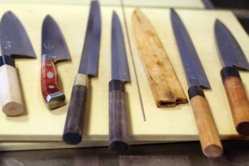 Part_Of_Suzukis_Knife_Kit Part of Suzuki's knife kit. 2 debas, 2 yanagis, the needle, a saya cover, and another yanagi and deba.