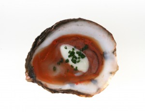 This oyster was fed a mixture of carrot juice, green cardamom, and aquarium salt that had been blended with a high-speed rotor-stator homogenizer to reduce the liquid's particle size below 10 microns. Larger particles could clog the oyster's gills.  The oyster ate the mixture and flavored itself while it was still alive.  It was served with crème fraîche and chives.
